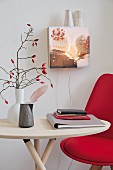 DIY-Wandleuchte aus Schaukasten mit Foto, davor Tisch mit rotem Stuhl