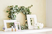 Ivy wreath, vintage picture frames and place cards hand-made from portraits stuck on corks on floating shelf