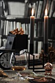 Cognacschwenker neben brennenden Kerzen und nostalgischer Uhr