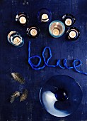 Tealight holders, glass dish and yarn lettering reading 'blue' on blue surface