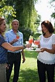 Drei Erwachsene mit Cocktail im Garten