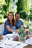 Couple seated at set garden table and glass jug of refreshing drink