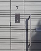 Moderne Eingangstür aus grauen Holzpaneelen mit Metallgriff (Ausschnitt)