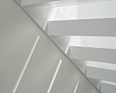 Detail of open white interior staircase with patterned of light and shade
