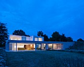 Modernes Architektenhaus in Flachbauweise mit grosszügigen Festerfronten im Abendlicht