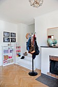 Bags hanging on coat stand next to foot of staircase in modern interior with open fireplace