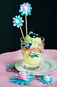Ice cubes, blueberries and paper flowers on swizzle sticks in glass