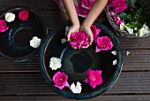 Roses floating in ceramic bowl and pink flower held in girl's hands