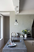Concrete worksurface with integrated sink and pendant lamps in restored period building