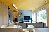 View from dining area into open-plan designer living area with TV against pastel-blue wall