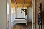 Modern four-poster bed in bedroom with old wooden floor