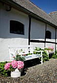 White-painted bench and flowering hydrangeas outside country house with exposed half-timber beams