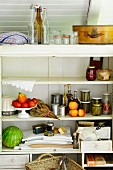 Preserving jars, kitchen utensils, vegetables and fruit in pantry