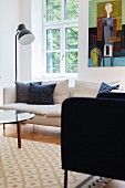 Armchair and standard lamp next to white sofa below lattice window and modern artwork