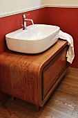 Countertop basin on rounded, exotic-wood base unit in renovated country-house bathroom with red wall below white dado rail