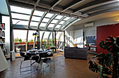 Essbereich und Lounge in offenem Wohnraum mit Metall- und Glaselementen