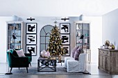Weihnachtlich dekoriertes Wohnzimmer mit Christbaum und symmetrischer Wanddekoration mit schwarz gerahmten Bildern und Vitrinenschränken
