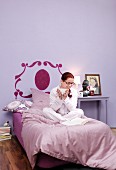 Woman in purple bedroom with bed headboard stencilled on wall