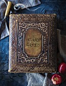 Antique, leather-bound book of fairy tales on blue surface as Halloween decoration