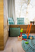 Modern wood-clad walls, window seat and wooden toys on oak floor in corner