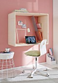 A homemade mini office on a pink wall – A wooden frame with an integrated desk and storage space made from taut ropes