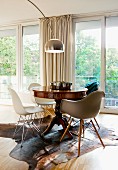 Modern shell chairs around antique table on cowhide rug