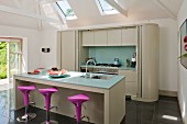 Island counter with bar stools and fitted counter with sliding door in modern kitchen