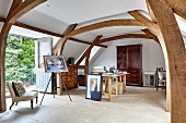 Atelier mit Staffelei und Arbeitstisch, sichtbare Holzkonstruktion mit gebogenen Stützen