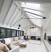 Pale sofa set in living room with exposed beams under roof ridge