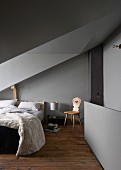 Grey walls and ceiling in attic bedroom with sloping ceiling and dormer window