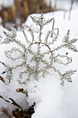 Metal and rhinestone snowflake ornament lying in snow