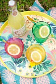 Summer drinks in colourful glasses on floral tray