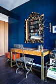 Opulent gilt-framed mirror on royal-blue wall above desk