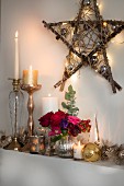 Candles and shiny ornaments below star made from branches and decorated with fairy lights