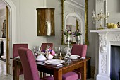Set table in elegant dining room with open fireplace and large mirror