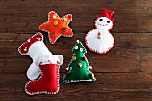 Hand-made felt Christmas decorations (stocking, snowman, Christmas tree and star) on wooden surface