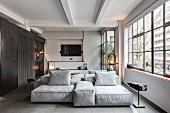 Sofa combination and factory windows in industrial loft apartment in shades of grey