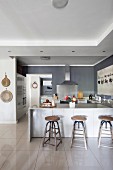 Breakfast bar and industrial-style bar stools in modern, open-plan kitchen