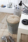 Round cushion on zinc bin used as office chair