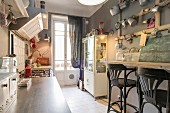 Breakfast bar, enamel tinware hung on wall and display case in vintage-style kitchen