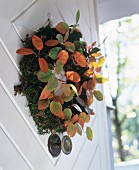 Wreath of moss and autumn leaves on open front door