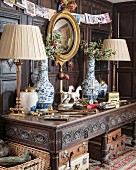 Table lamps and holly in Oriental vases on antique table