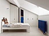Child's attic bedroom with wardrobes fitted under sloping ceiling