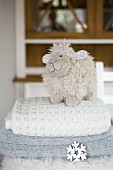 Plush sheep on stack of woollen blankets