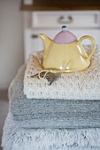 Pastel teapot on stack on woollen blankets