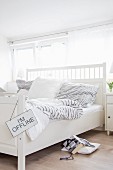 White double bed with headboard and grey and white striped bed linen in Scandinavian-style bedroom