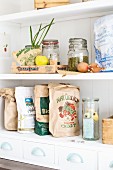 Various recycled paper bags, storage jars and fruit crates on kitchen shelves