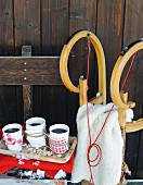 White china beakers of mulled wine with fabric holders and wooden sledge outside rustic hut
