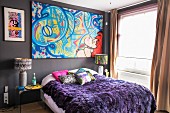 Colourful graffito-style artwork above bed with purple fur blanket