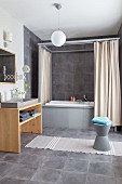 Grey tiles and bath with four-poster frame and shower curtains in bathroom